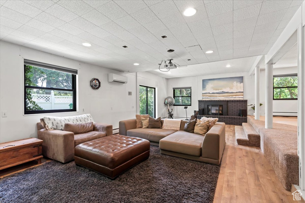 Living room featuring a wall mounted AC, light wood finished floors, plenty of natural light, and recessed lighting