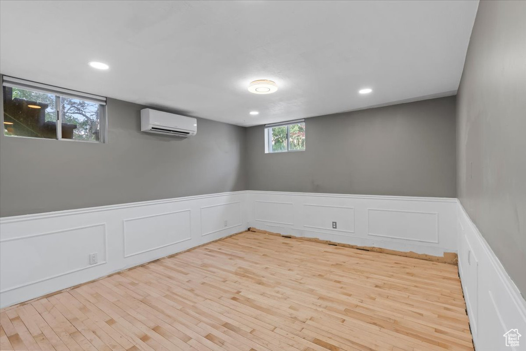Unfurnished room with an AC wall unit, wood finished floors, wainscoting, a decorative wall, and recessed lighting