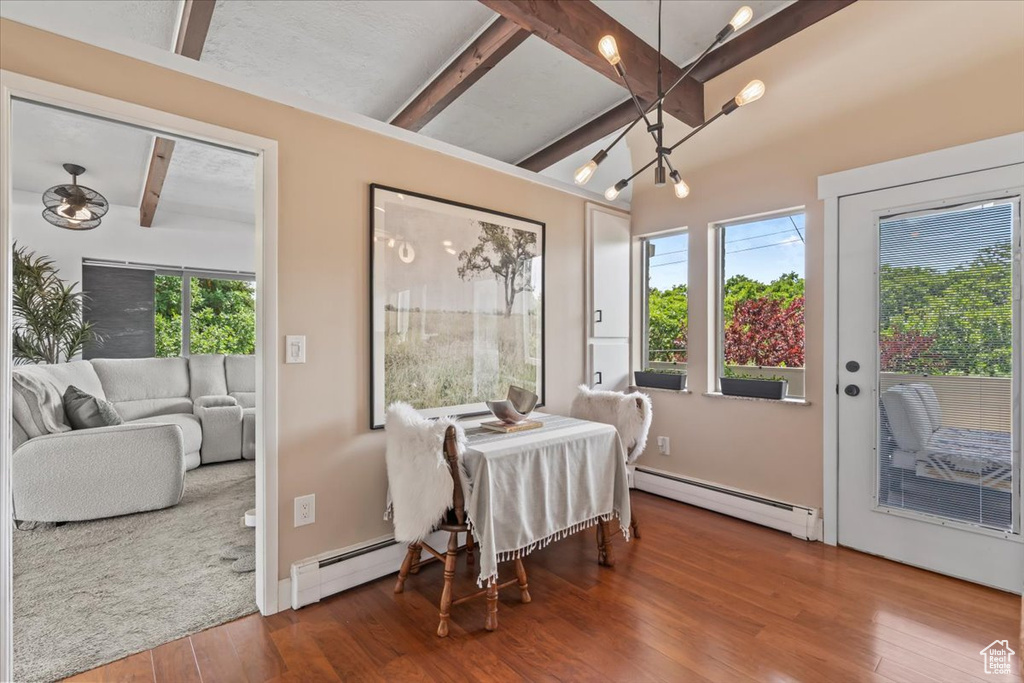 Dining area with baseboard heating, beamed ceiling, wood finished floors, a chandelier, and a ceiling fan