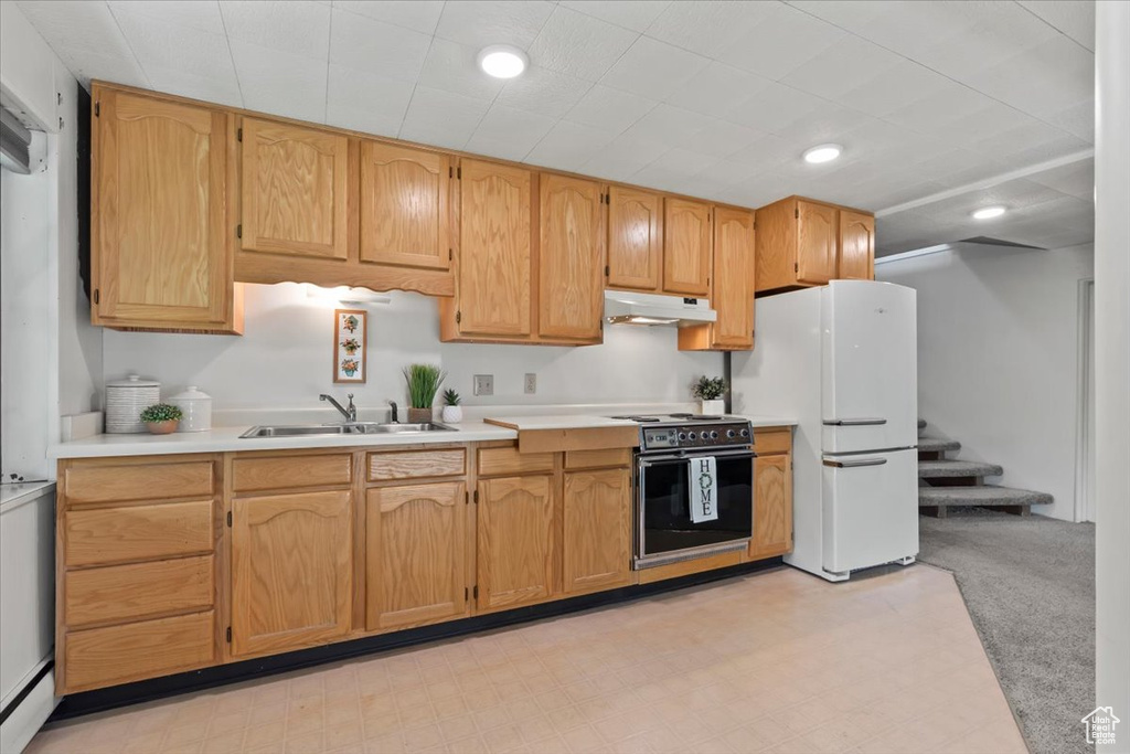 Kitchen featuring range with electric stovetop, under cabinet range hood, freestanding refrigerator, light countertops, and light colored carpet