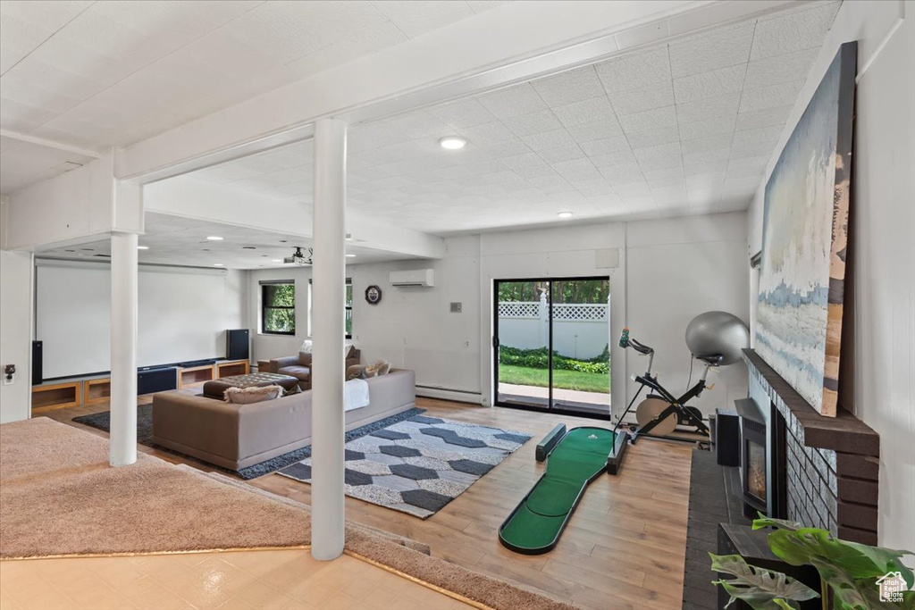 Exercise room featuring a wall mounted AC, wood finished floors, a fireplace, a baseboard radiator, and recessed lighting