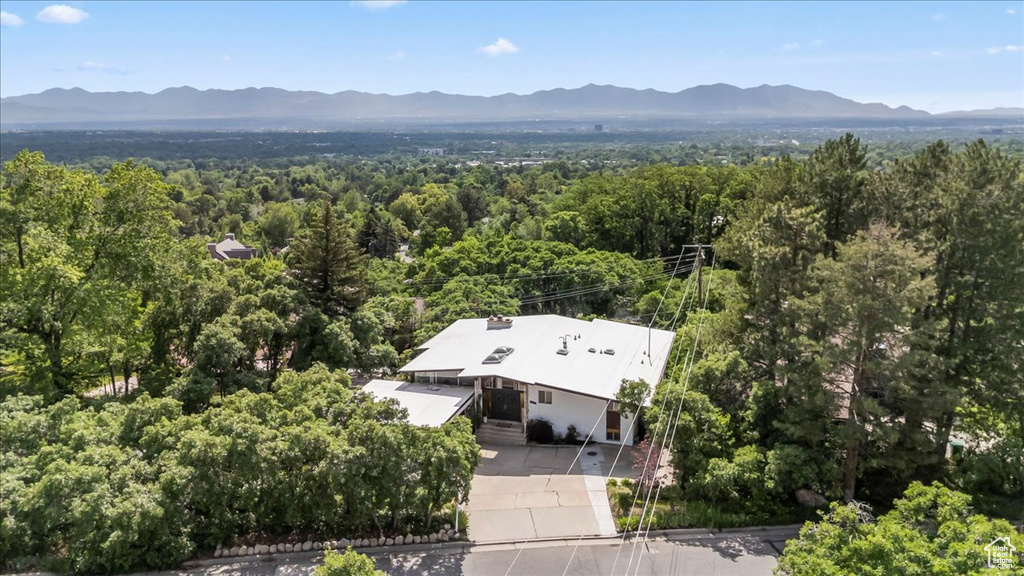 Aerial view of property and surrounding area with a mountain backdrop and a heavily wooded area