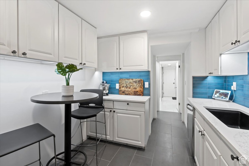Kitchen featuring backsplash, white cabinetry, dark tile patterned flooring, recessed lighting, and dishwasher