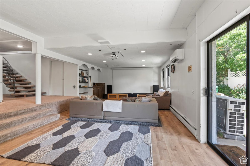 Living area featuring a baseboard heating unit, light wood-type flooring, an AC wall unit, stairway, and recessed lighting