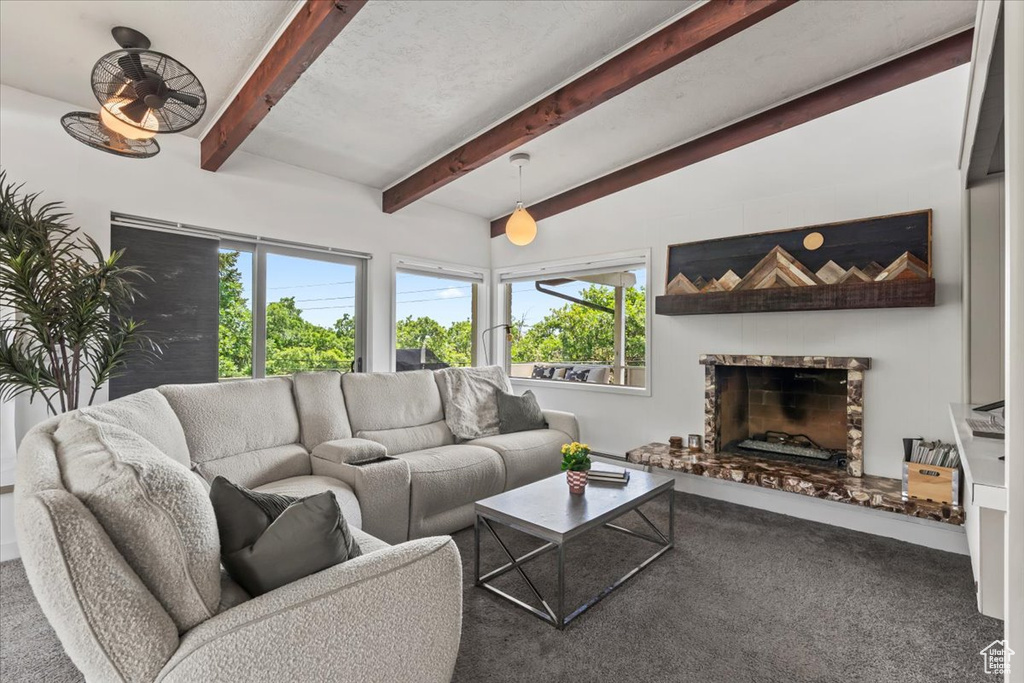 Carpeted living room featuring a fireplace with raised hearth and beamed ceiling