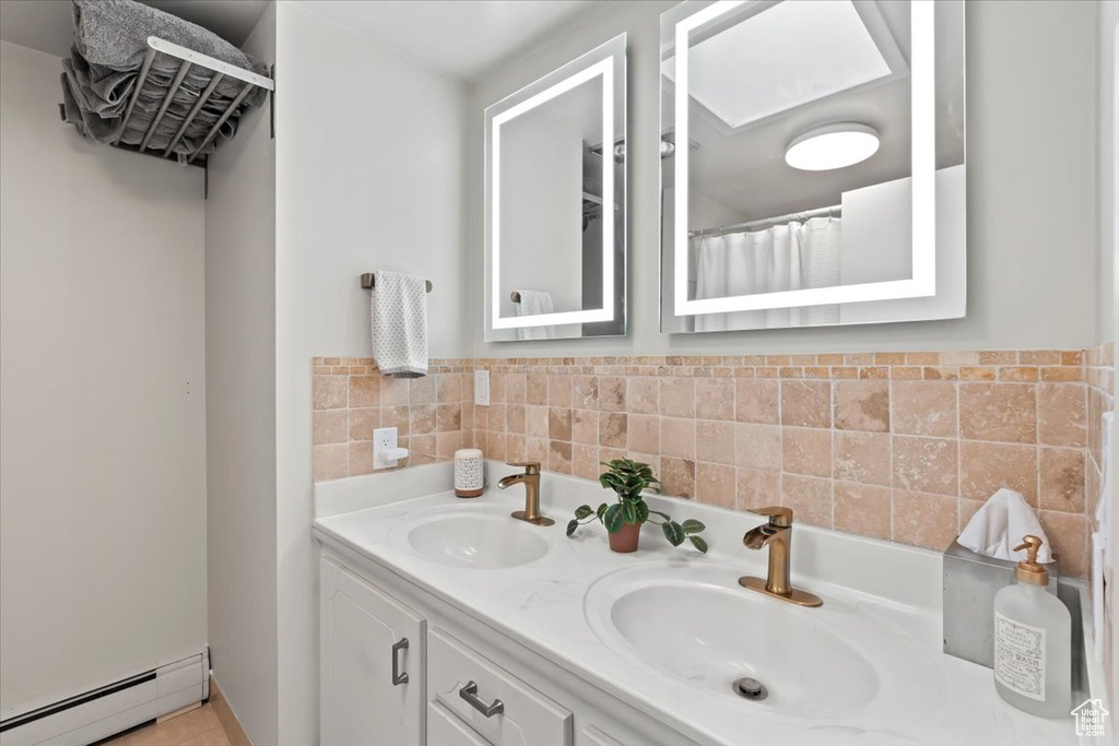 Full bathroom featuring a baseboard radiator and double vanity