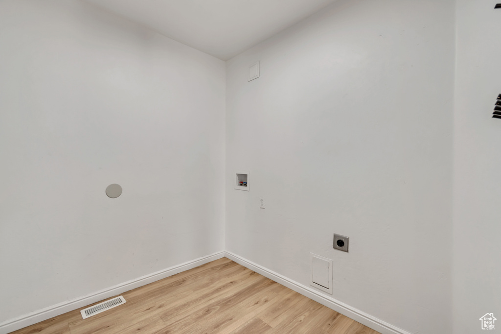 Laundry room with hookup for a washing machine, electric dryer hookup, and light wood-style floors