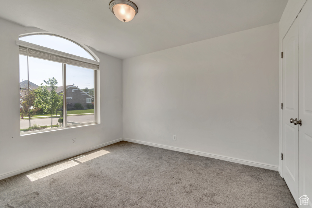 Carpeted spare room with baseboards and vaulted ceiling