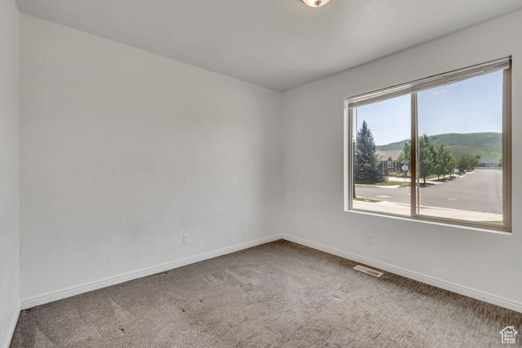 Carpeted spare room featuring baseboards and a mountain view