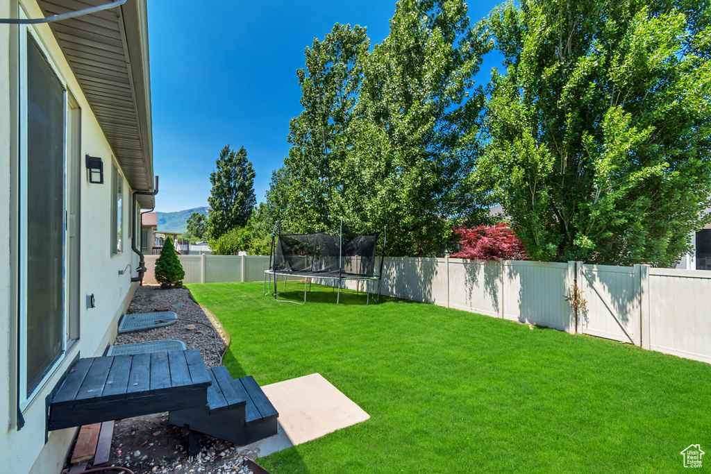 Fenced backyard featuring a trampoline