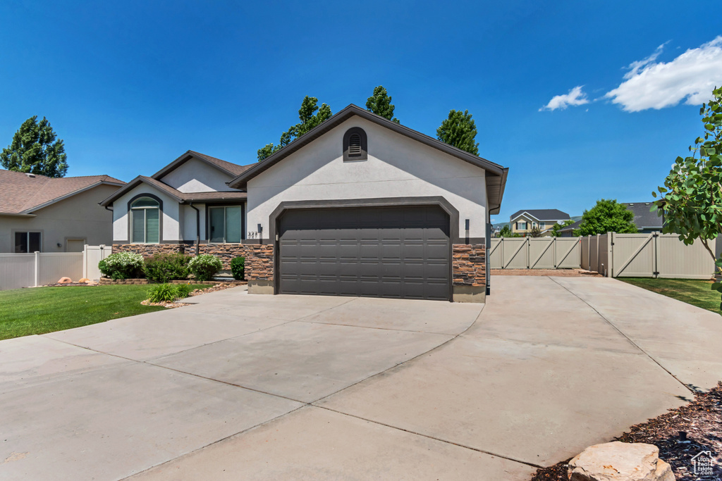 Ranch-style house featuring a gate, stucco siding, stone siding, and concrete driveway
