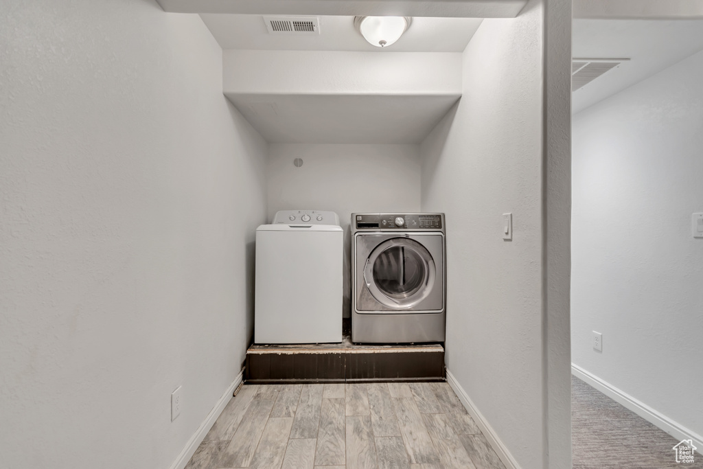 Washroom featuring separate washer and dryer and wood finished floors