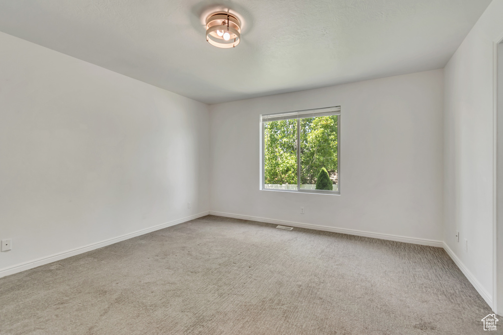 Carpeted spare room featuring baseboards