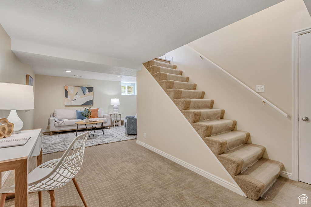 Stairs featuring carpet floors and a textured ceiling