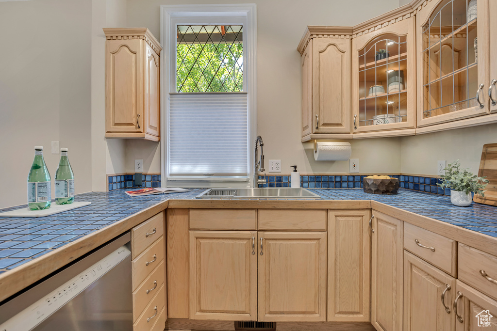 Kitchen featuring light brown cabinetry, dishwasher, and glass insert cabinets