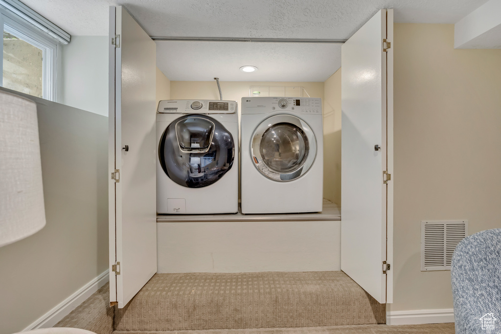 Washroom featuring washing machine and dryer and carpet floors
