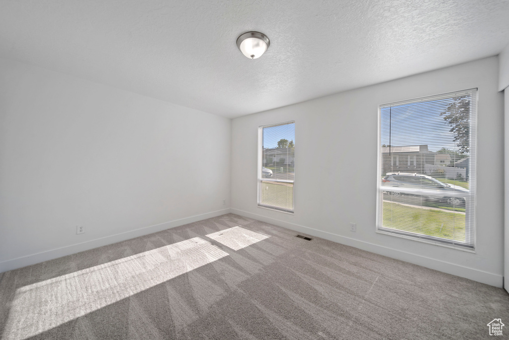 Carpeted empty room featuring baseboards and a textured ceiling