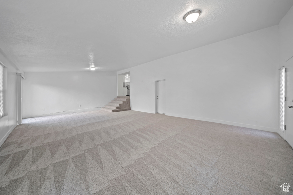 Carpeted empty room with a textured ceiling and baseboards