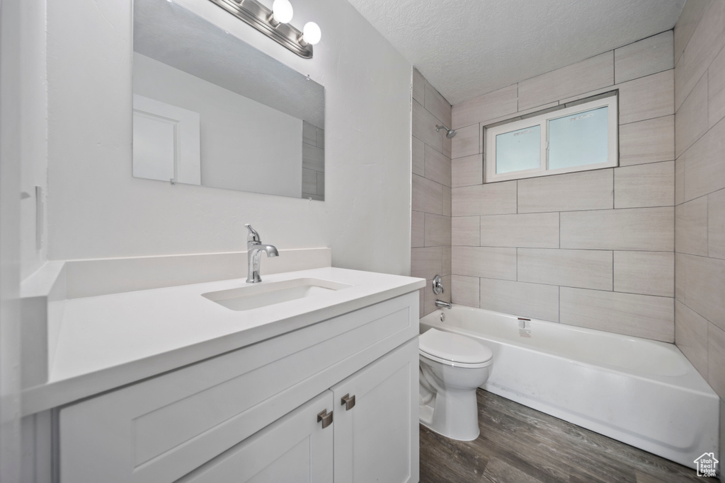 Full bathroom featuring vanity, wood finished floors, shower / tub combination, and a textured ceiling