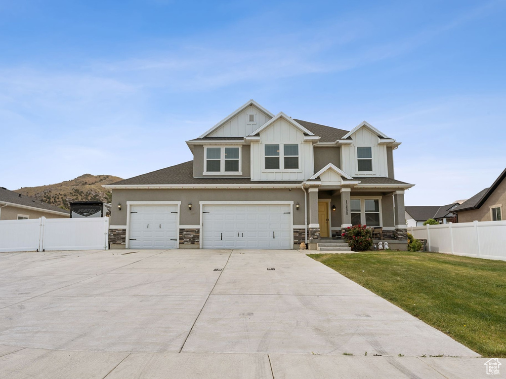 Craftsman inspired home featuring driveway, stone siding, board and batten siding, covered porch, and an attached garage