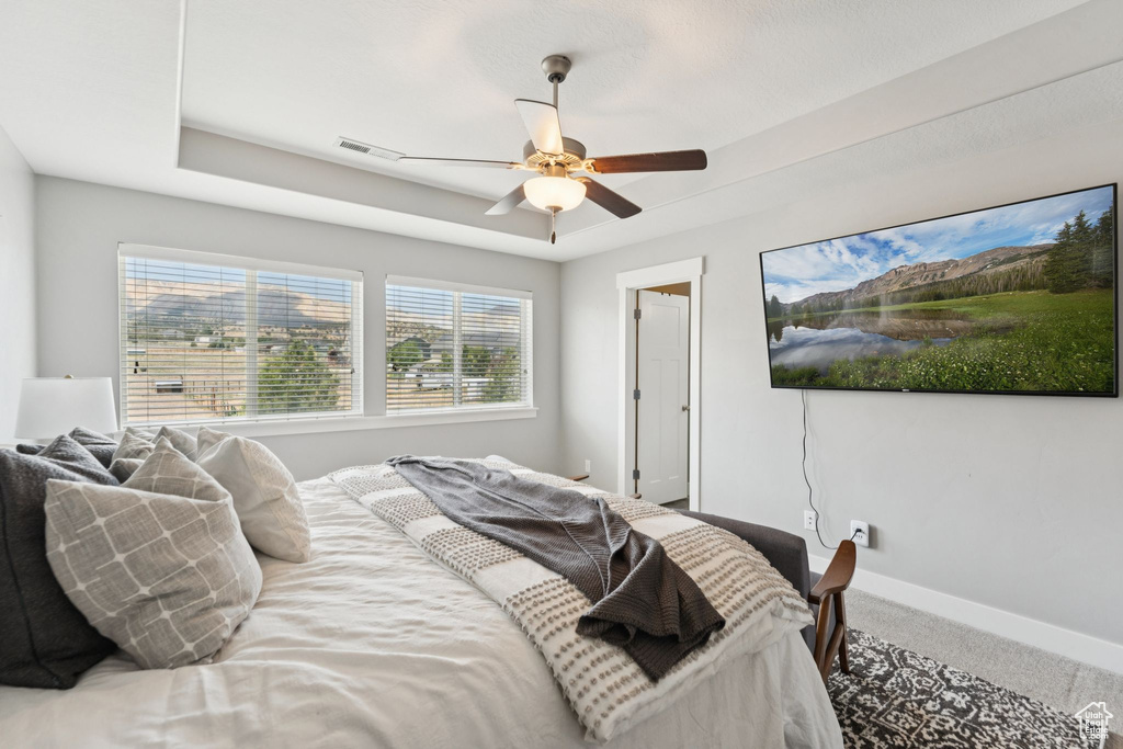 Bedroom with carpet flooring, multiple windows, and ceiling fan