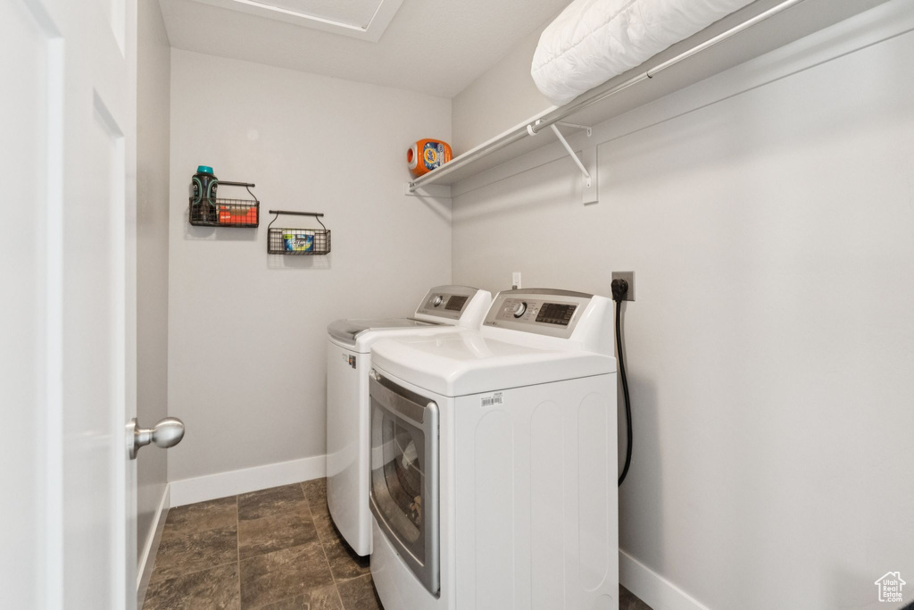 Laundry room featuring independent washer and dryer and dark stone finish floors