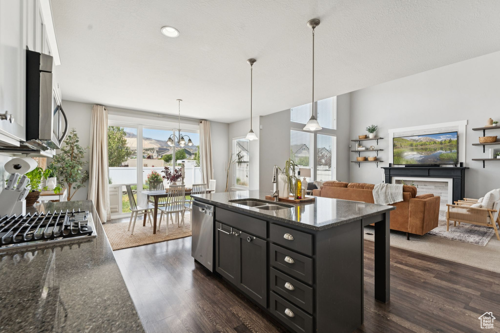 Kitchen featuring appliances with stainless steel finishes, dark wood-style floors, healthy amount of natural light, dark stone countertops, and recessed lighting