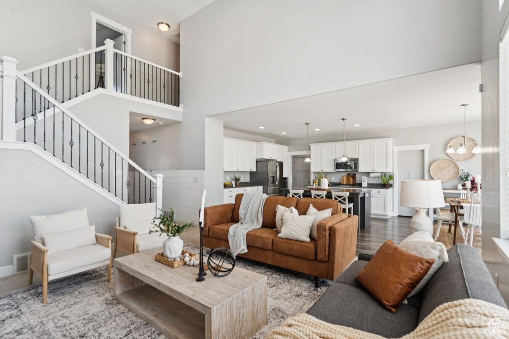Living area with stairs, a chandelier, a high ceiling, and recessed lighting