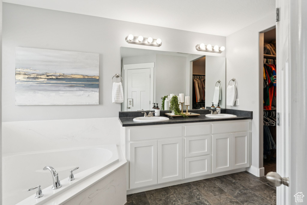 Bathroom featuring double vanity, a garden tub, and a spacious closet