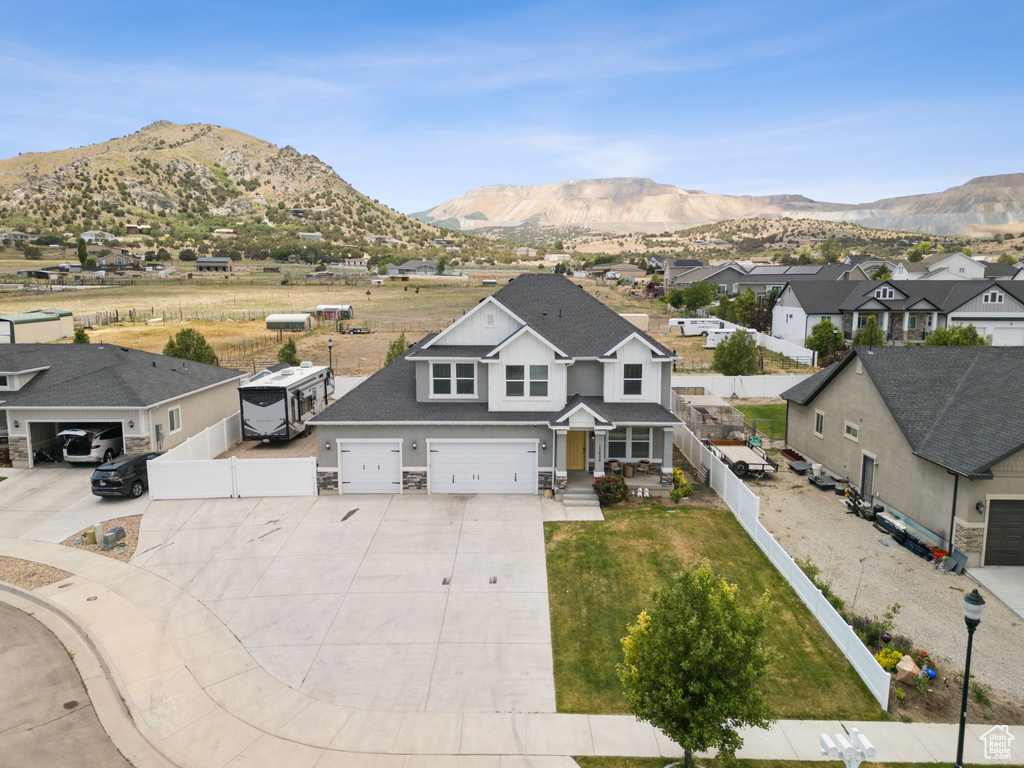 View of front of home with concrete driveway, a mountain view, a residential view, stone siding, and an attached garage