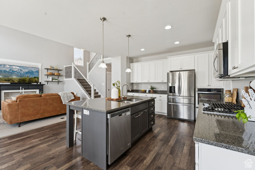Kitchen with appliances with stainless steel finishes, dark wood-style flooring, recessed lighting, a kitchen bar, and white cabinets