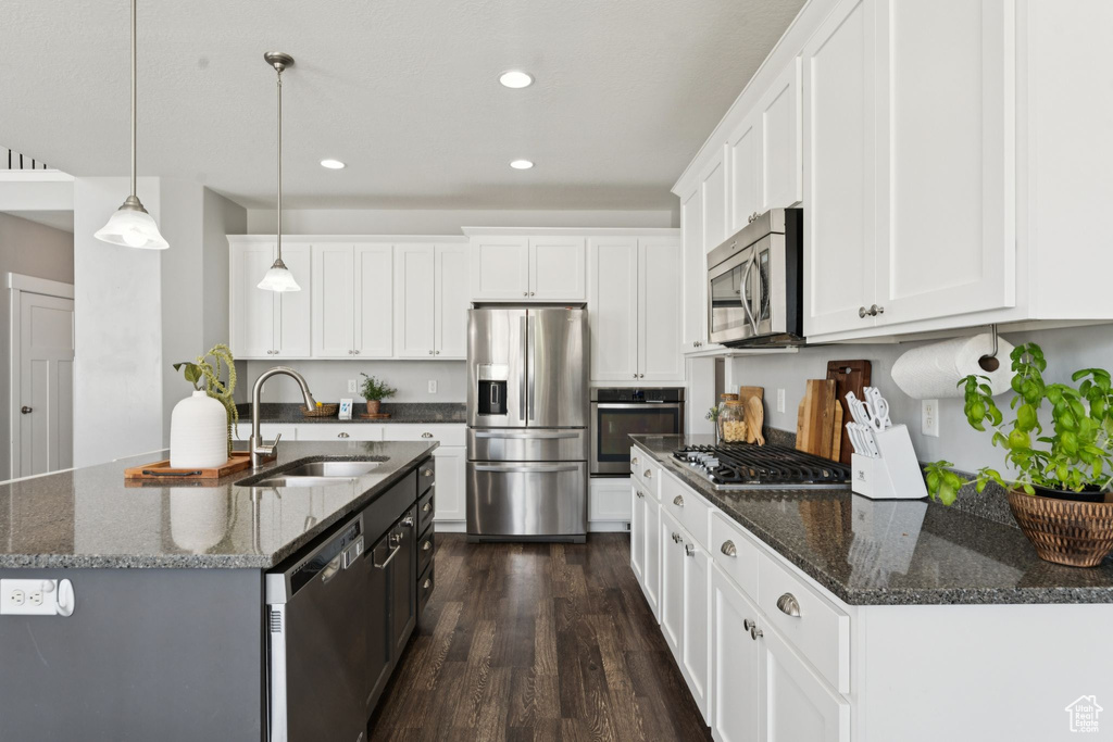 Kitchen with stainless steel appliances, recessed lighting, dark wood-style flooring, white cabinetry, and decorative light fixtures