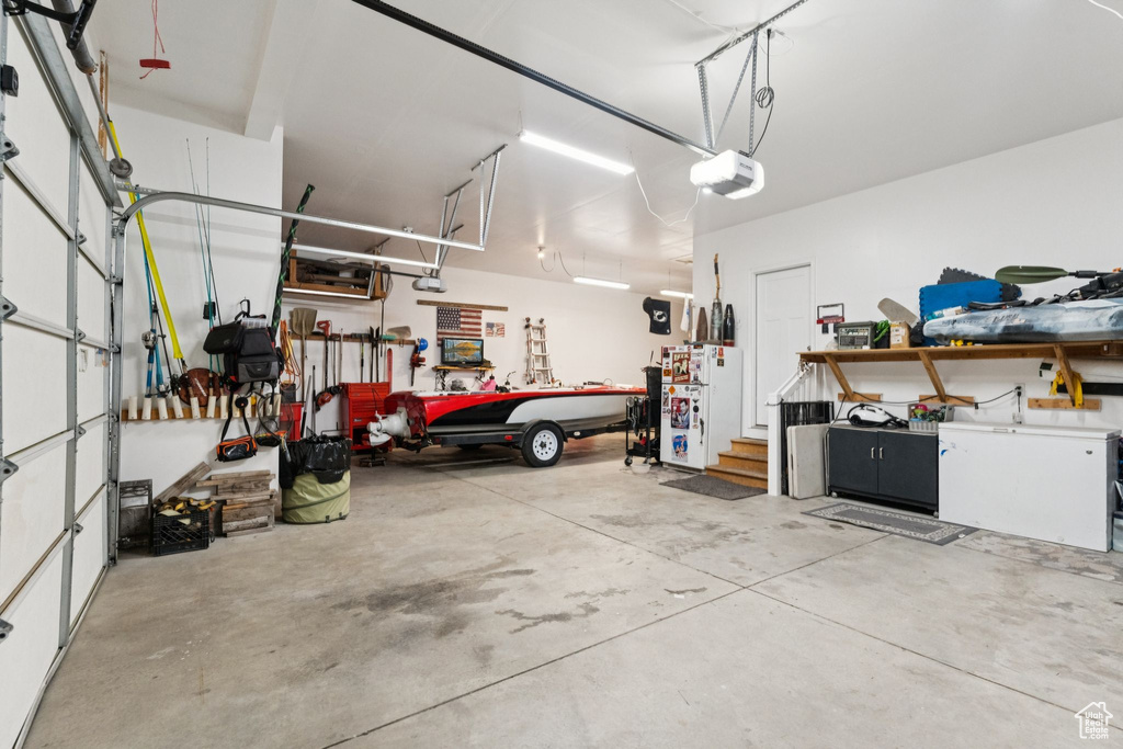 Garage with a workshop area, a garage door opener, and freestanding refrigerator