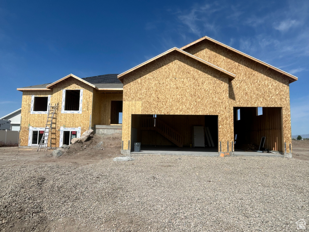 Unfinished property with an attached garage, gravel driveway, and stucco siding