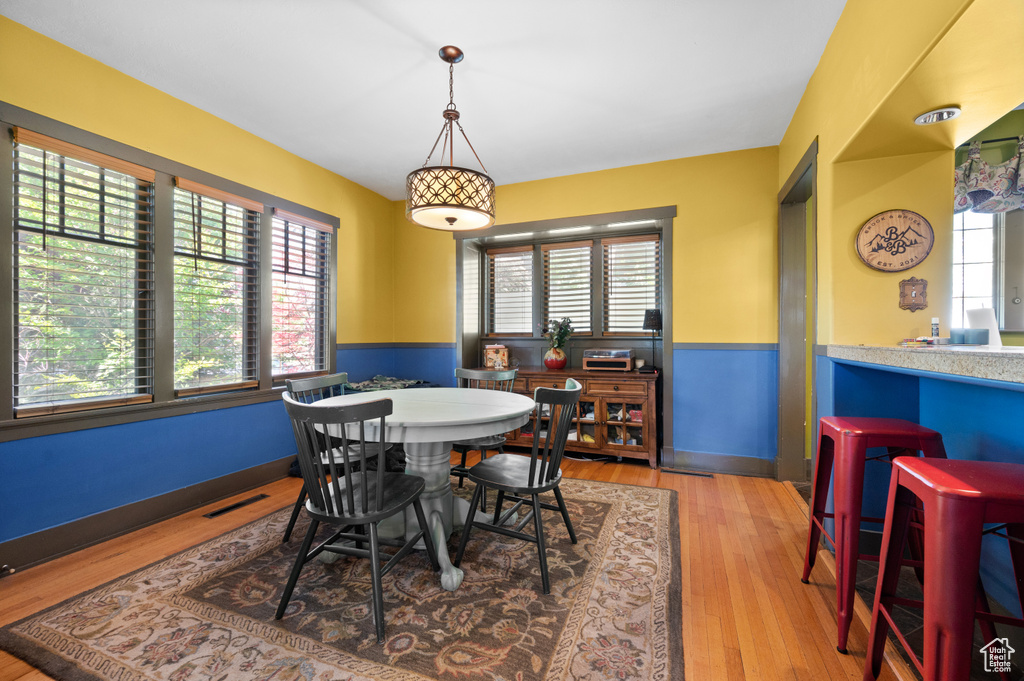 Dining space with wood finished floors and a wainscoted wall
