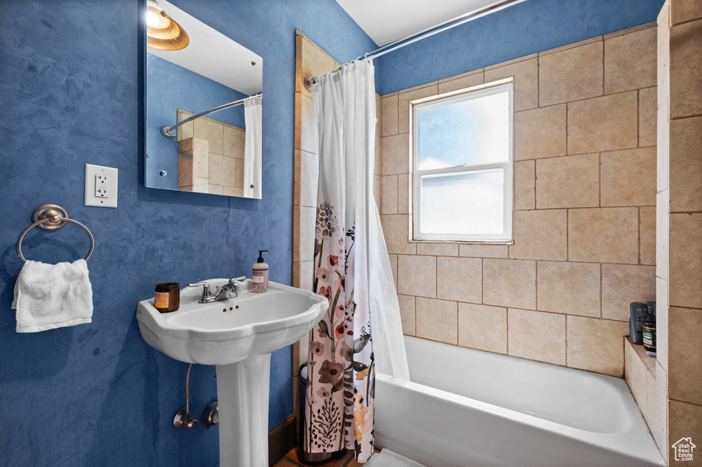 Bathroom featuring shower / bath combo with shower curtain and a sink