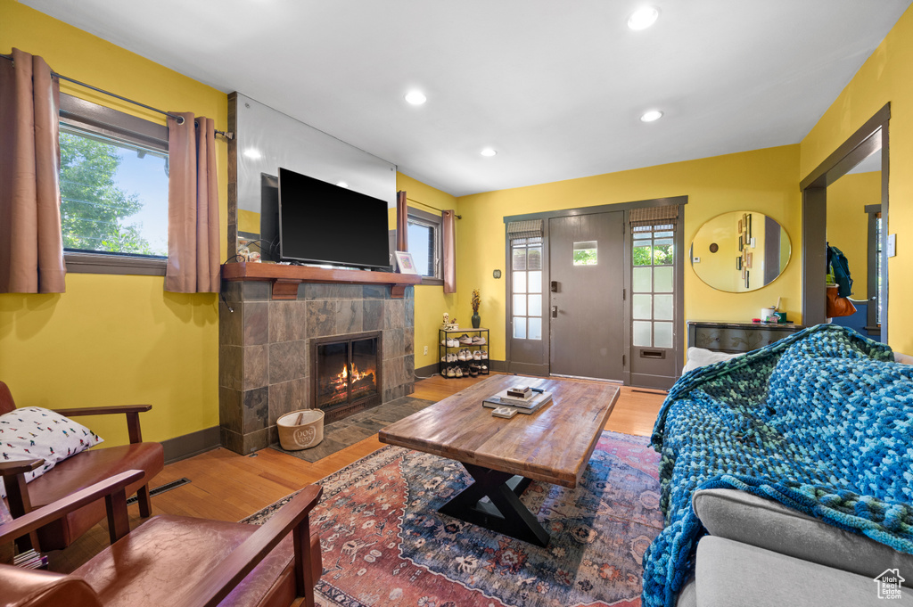 Living area featuring wood finished floors, healthy amount of natural light, a tiled fireplace, and recessed lighting