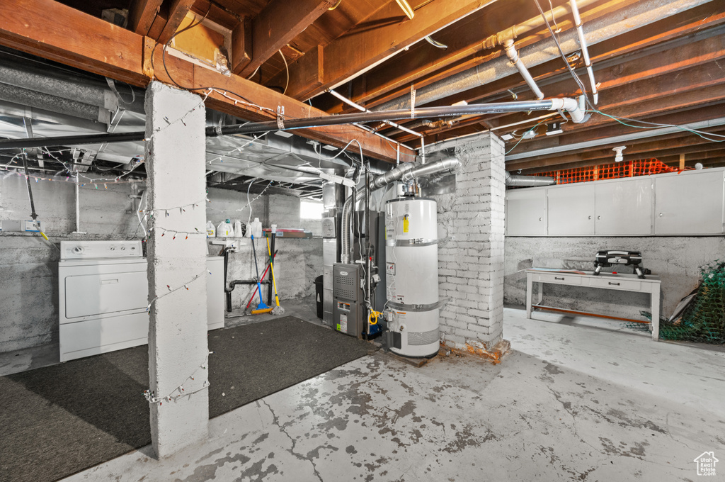 Unfinished basement featuring water heater, washer / clothes dryer, and heating unit