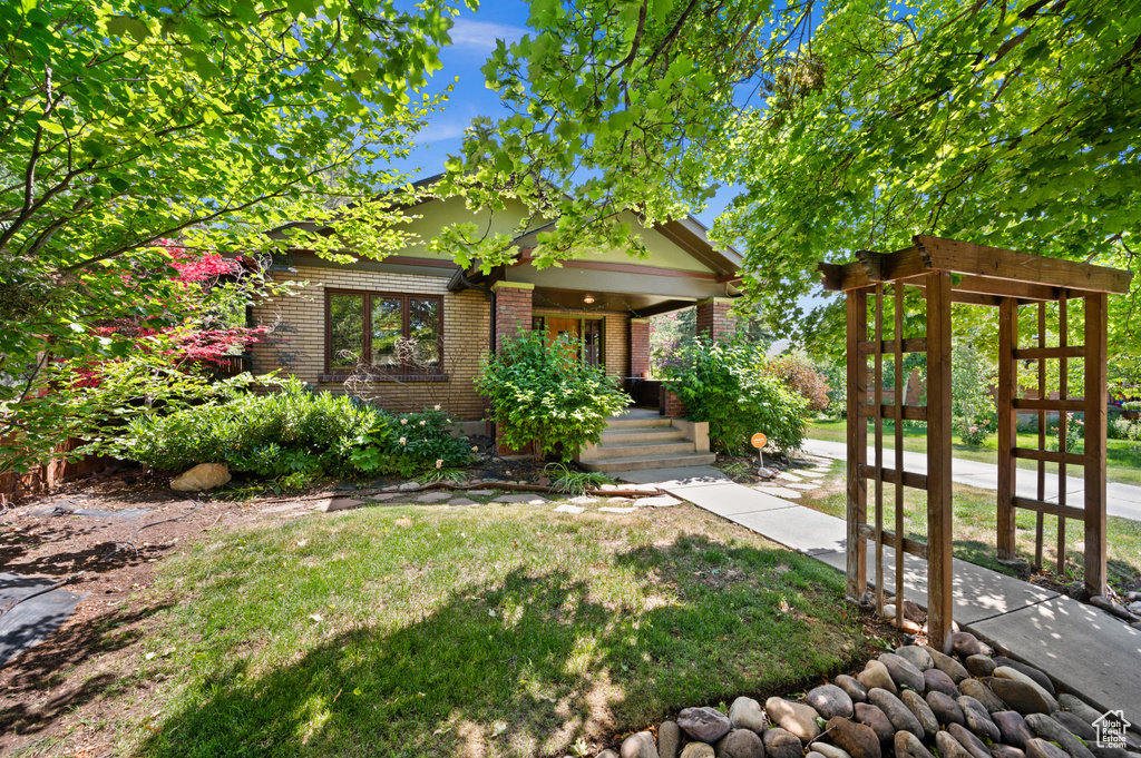 View of front of house featuring brick siding, covered porch, and a front yard