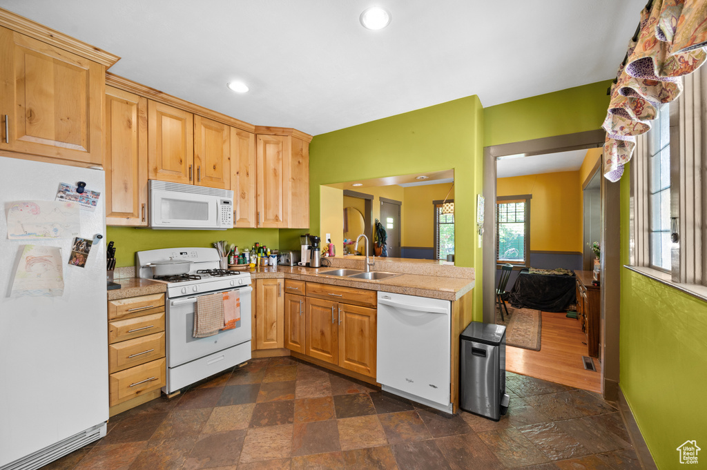 Kitchen featuring white appliances, dark stone finish floors, light brown cabinets, recessed lighting, and a peninsula