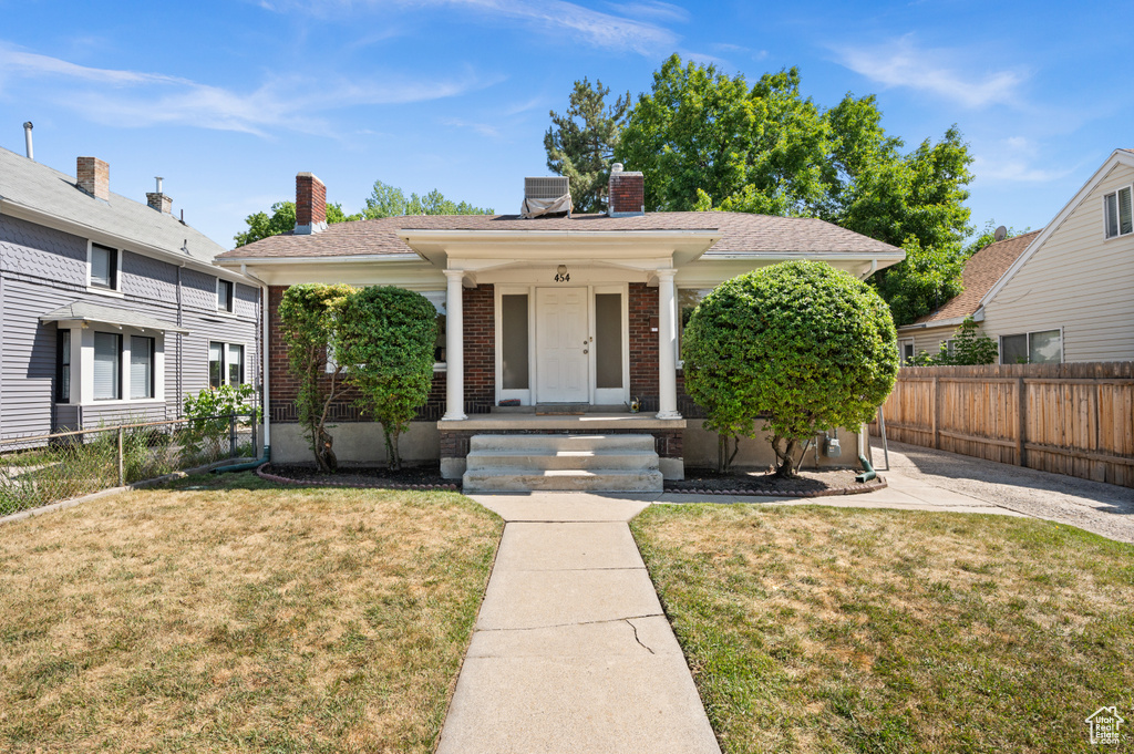 View of front of house with a porch, brick siding, and a chimney