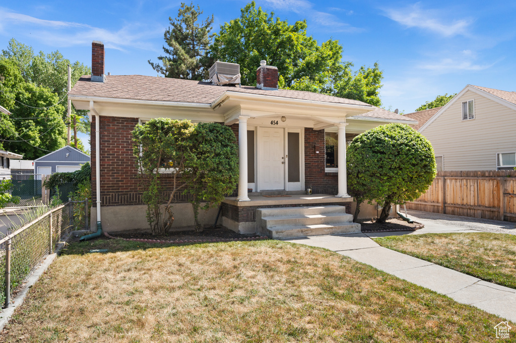 View of front facade featuring a chimney, brick siding, and a porch