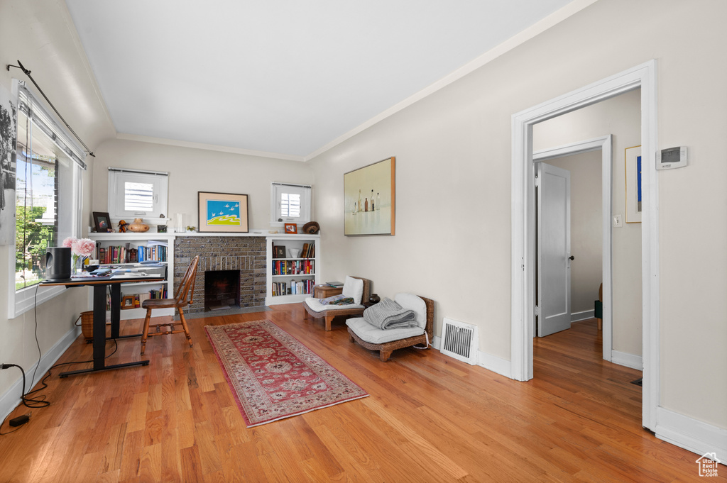 Living area featuring wood finished floors, a fireplace, and ornamental molding