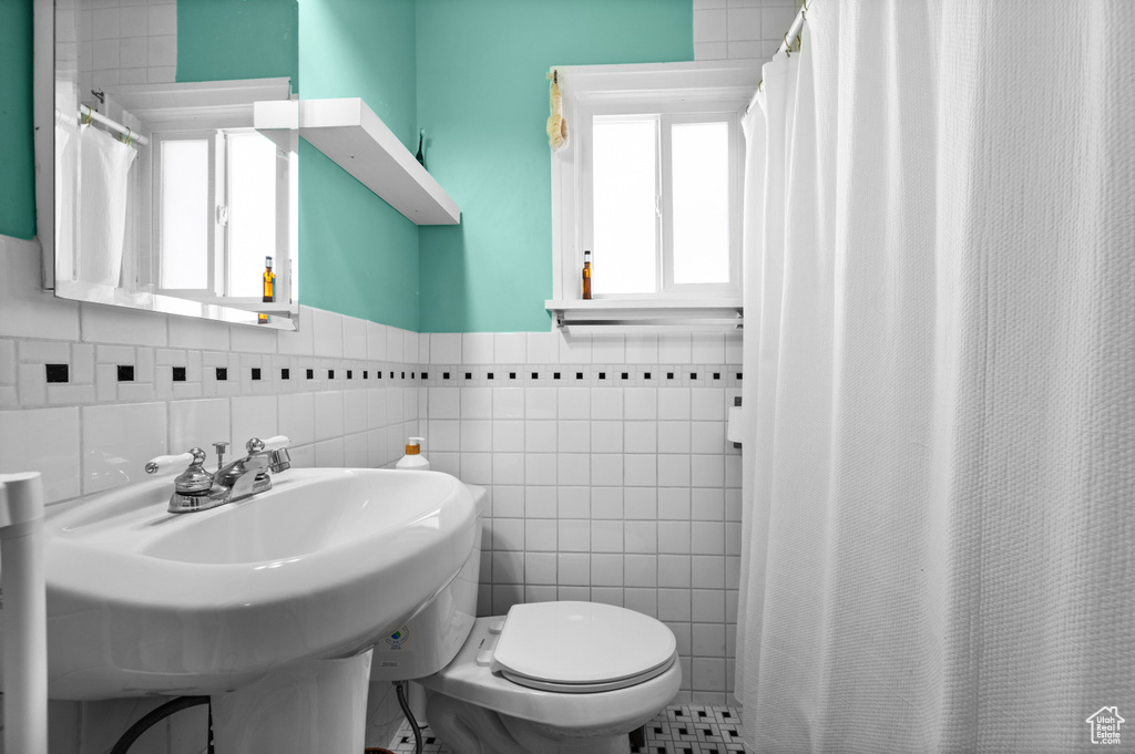 Full bathroom with a wainscoted wall, tile walls, and curtained shower