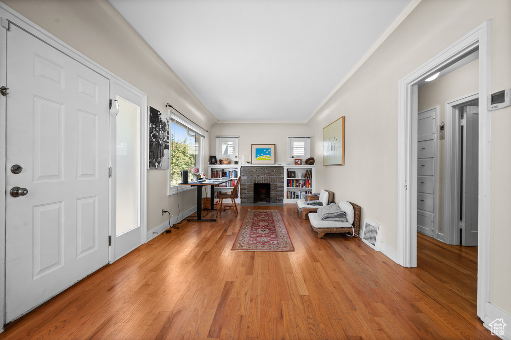 Entrance foyer featuring light wood-type flooring, ornamental molding, and a fireplace