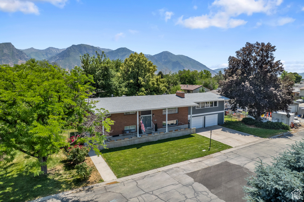 View of front of house with a garage, driveway, a front yard, a mountain view, and brick siding