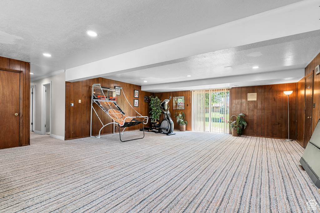 Workout room with a textured ceiling, wood walls, carpet, and recessed lighting