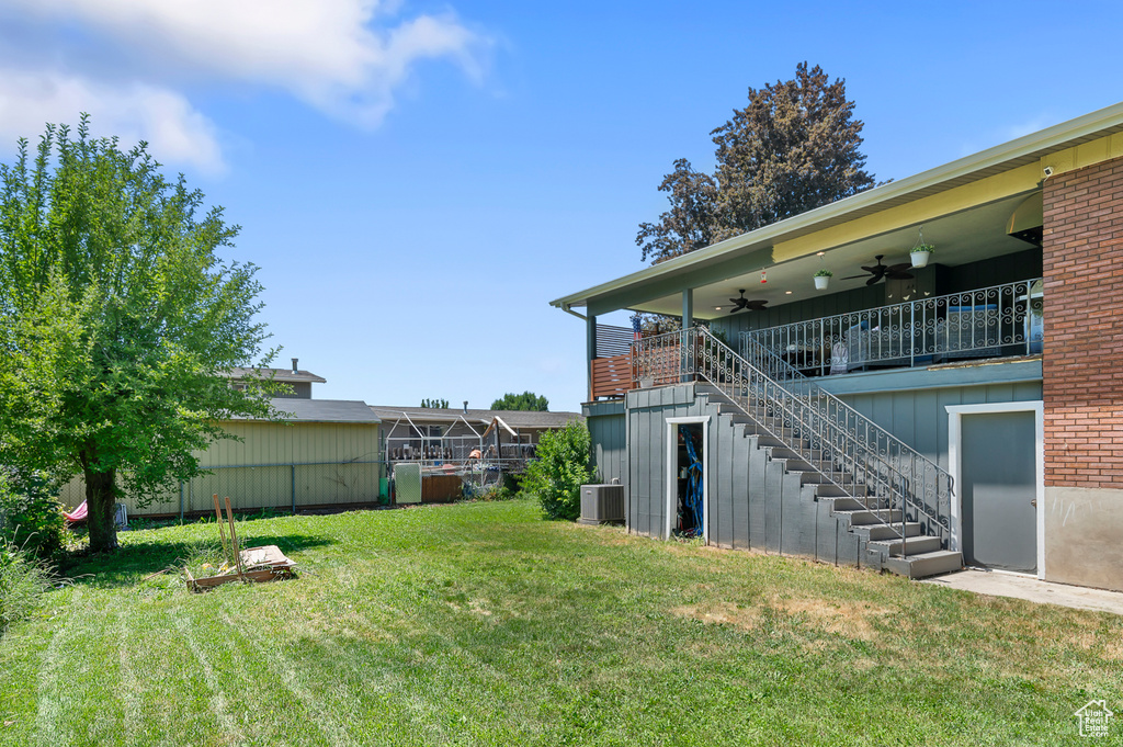 View of grassy yard with a ceiling fan and stairway