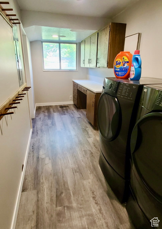 Laundry room featuring cabinet space, washer and clothes dryer, light wood finished floors, and an office area