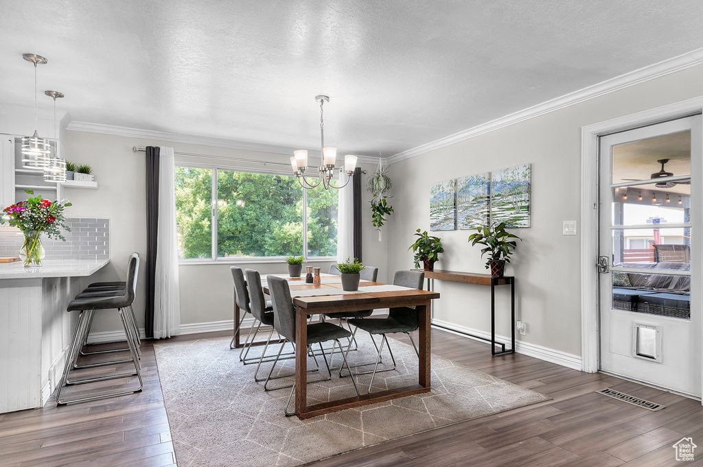 Dining room with a chandelier, wood finished floors, and crown molding